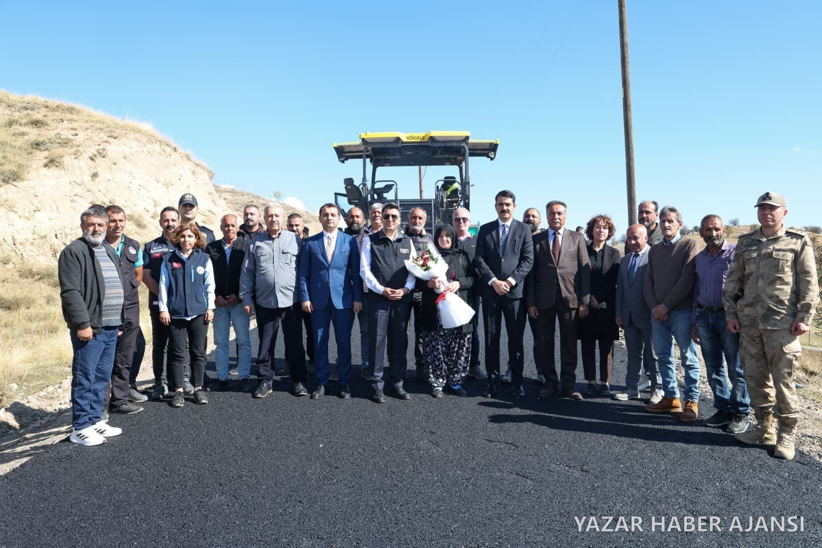 Vali Şefik Aygöl ve katılımcılar, Pertek'in Pirinçci Köyü'nde yeni serilen asfaltta toplu fotoğraf çektirdi (Fotoğraf: Tunceli Valiliği)
